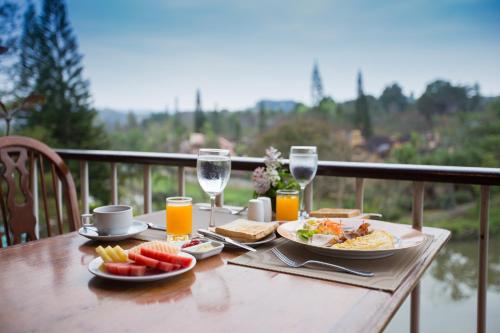 une table en bois avec des assiettes de nourriture et des verres de vin dans l'établissement Imperial Phukaew Hill Resort, à Khao Kho