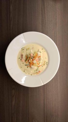 a white plate of soup on a wooden table at Bardu Hotell in Setermoen