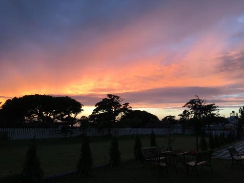a sunset with chairs and tables in a yard at Summer Homestay in Kenting