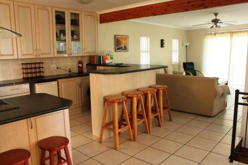 a kitchen with a counter and stools in a room at Kian's Place Holiday Home in Langebaan