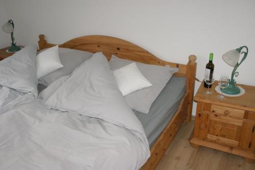 - une chambre avec un lit doté d'oreillers blancs et d'une table de nuit dans l'établissement Beim Landarzt, à Rabenholz