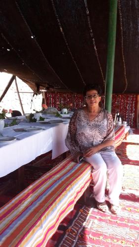 a woman sitting on a bench under a table at Ferme D"Hote Lala Fatima in Aïn Leuh