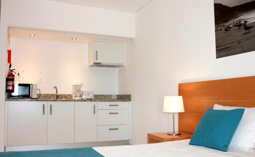 a white bedroom with a bed and a kitchen at Casa Praia Mar in Salema