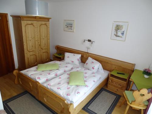 a small bedroom with a wooden bed with green pillows at Pension Bayrhammer in Faistenau