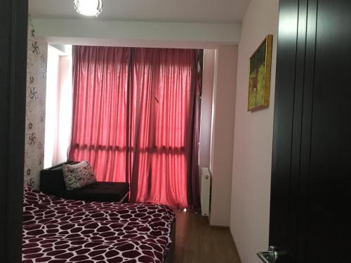 a bedroom with a bed and a window with red curtains at Apart 516 Bobline in Bakuriani
