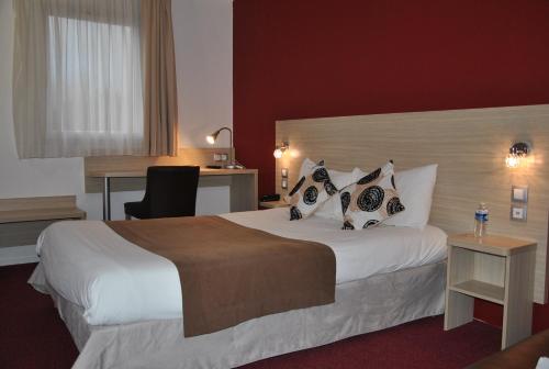 a hotel room with a large bed and a desk at Logis Hotel Altina in Pacy-sur-Eure
