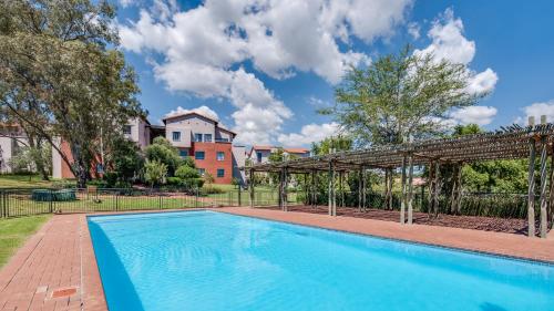 a swimming pool with a pergola next to a building at JoziStay @ Jackal Creek Apartments in Roodepoort
