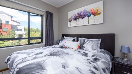a bedroom with a large bed and a window at JoziStay @ Jackal Creek Apartments in Roodepoort
