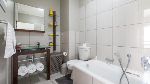 a white bathroom with a toilet and a sink at JoziStay @ Jackal Creek Apartments in Roodepoort