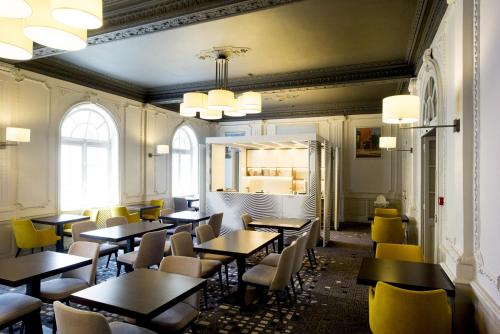a dining room with tables and yellow chairs at Hôtel Mercure Rodez Cathédrale in Rodez