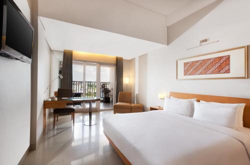 Habitación de hotel con cama y escritorio en The Capital Hotel Surabaya en Surabaya