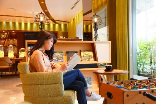 a woman sitting in a chair reading a book at Kyoto Tower Hotel Annex in Kyoto