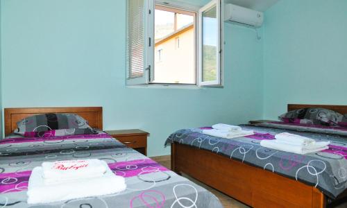 two twin beds in a room with a window at Apartmani Bulajic in Tivat