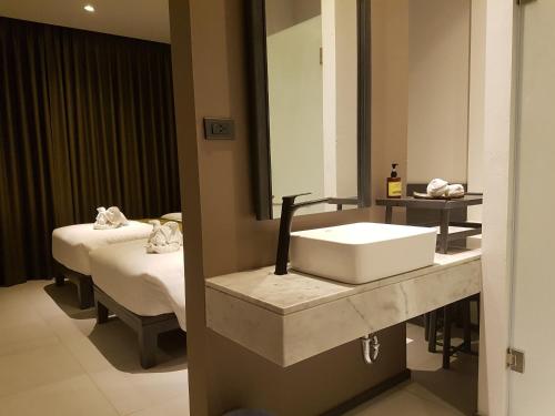 a bathroom with a sink and a mirror and a bed at Maehaad Bay Resort - SHA Plus in Mae Haad