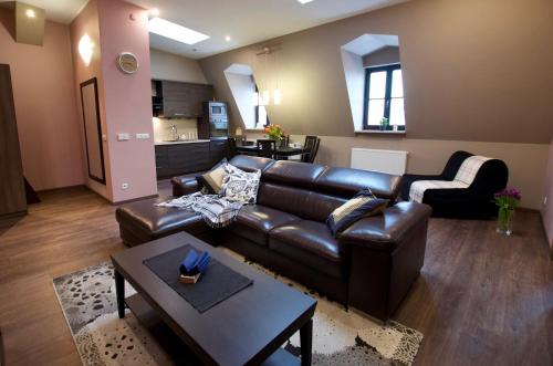 a living room with a leather couch and a table at 7 Koron - Exclusive Apartments in Kraków