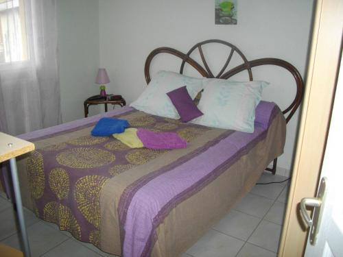 a bedroom with a bed with purple sheets and pillows at La Nouste Maisoun in Barcelonne-du-Gers