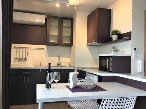a kitchen with black and white cabinets and a table with wine glasses at Sky Apartments in Blagoevgrad