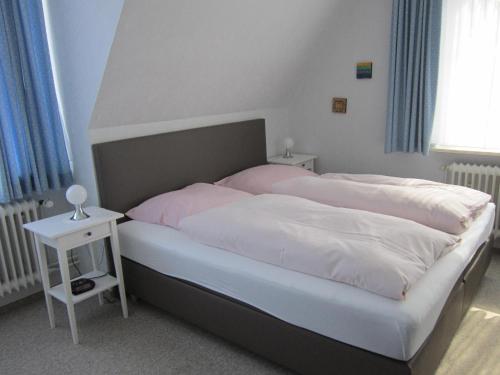 a bedroom with a bed with pink sheets and a side table at Hotel Möllner Hof in Welt