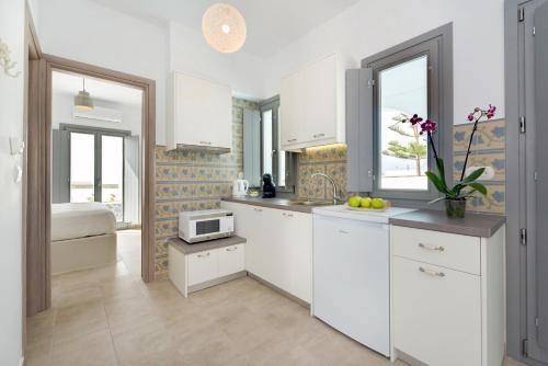 a kitchen with white cabinets and a microwave at White Harmony Suites in Megalokhori