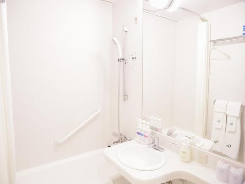 Baño blanco con lavabo y espejo en Hotel Fukuoka Garden Palace, en Fukuoka