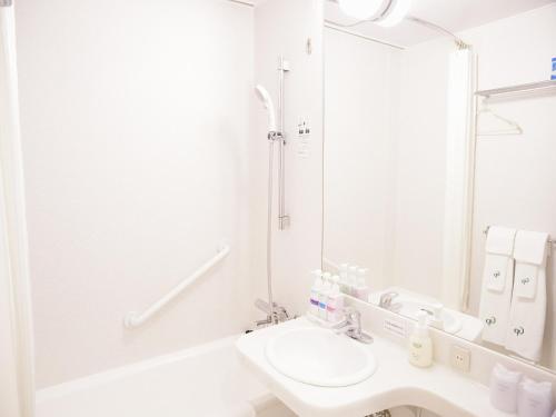 a white bathroom with a sink and a mirror at Hotel Fukuoka Garden Palace in Fukuoka