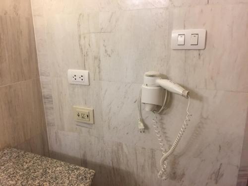 a phone is hanging on a wall in a bathroom at Fortune Hotel Korat- SHA Plus in Nakhon Ratchasima
