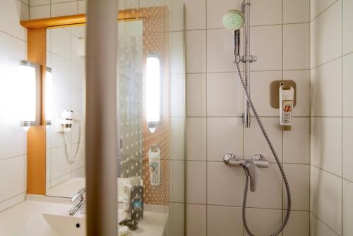 a bathroom with a shower, sink, and mirror at ibis Utrecht in Utrecht