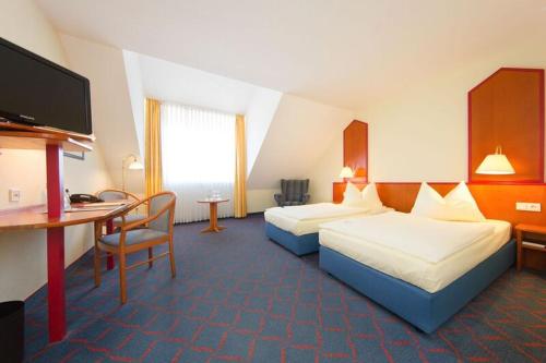 a hotel room with two beds and a desk at Hotel Montana in Guxhagen