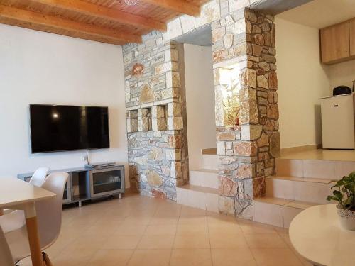 a living room with a tv and a stone wall at Nafplio cozy mountain cottage in Nafplio