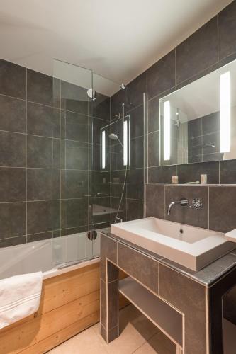 a bathroom with a tub and a sink and a bath tub at Résidence Pierre & Vacances Premium Les Chalets du Forum in Courchevel