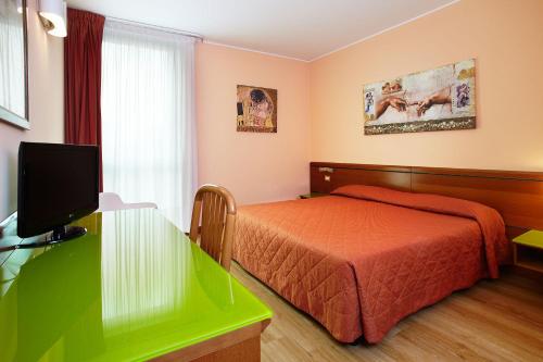 a bedroom with a bed and a desk with a television at Primhotel in Oderzo