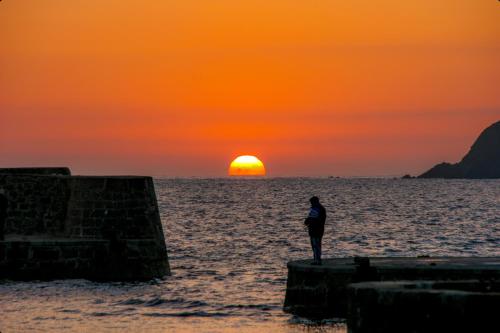 a person standing on a pier watching the sunset at Aparportu in Mundaka
