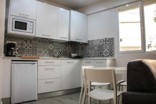 a kitchen with white cabinets and a table and chairs at Aparportu in Mundaka