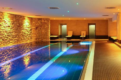 a swimming pool in a hotel with a stone wall at Dorint Resort Winterberg in Winterberg