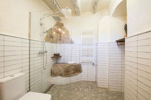 ein weiß gefliestes Bad mit einem WC und einem Felsen in der Unterkunft Mas del Sord 1335 in La Selva del Camp