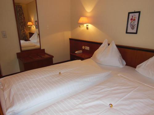 a bedroom with a white bed with a large mirror at Wohlfühlresort und Feriengut Martinerhof in Sankt Martin am Tennengebirge