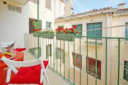 a balcony with a red table and chairs and a building at Calle dei Fabbri Apartment in Venice