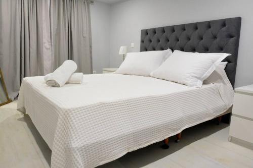 un letto bianco con testiera nera e cuscini bianchi di Liston Apartment a Città di Corfù