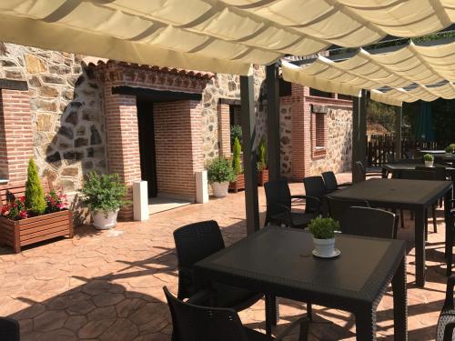 a patio with tables and chairs under an umbrella at Hotel Rural La Cabrera in Robledo del Buey