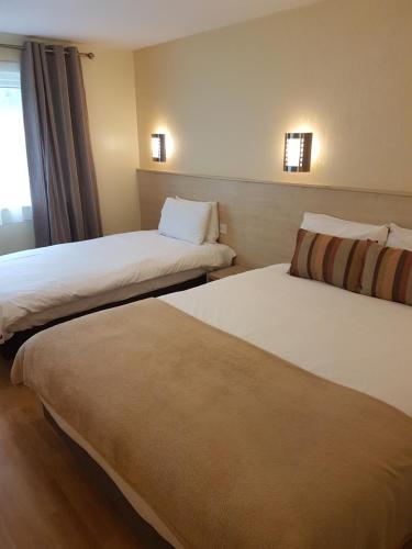 a hotel room with two beds and a window at Travel Plaza Hotel in Desborough