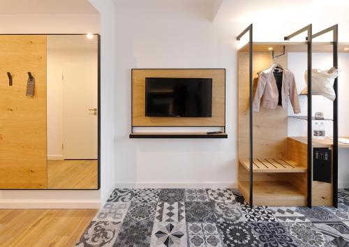 a room with a tv and a wall with a mirror at Coffee Fellows Hotel Dortmund in Dortmund