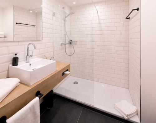 a white bath tub sitting next to a white sink at Coffee Fellows Hotel Dortmund in Dortmund