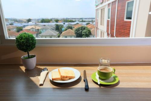 una mesa con un plato de tostadas y una taza de café en Triple Trees Hotel en Pathum Thani