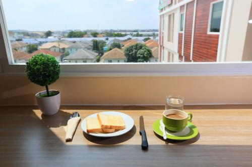 a table with a plate of toast and a cup of coffee at Triple Trees Hotel in Pathum Thani