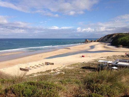 a sandy beach with umbrellas and the ocean at Apartamento acolhedor numa das mais belas praias do centro de Portugal in Pataias