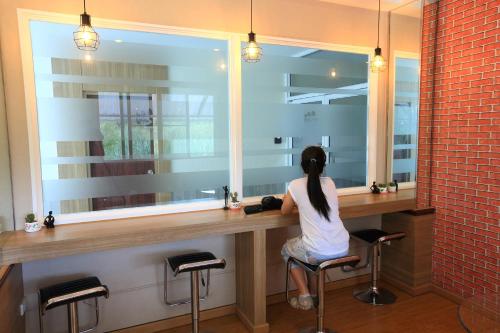 a woman sitting at a counter in front of a mirror at Triple Trees Hotel in Pathum Thani