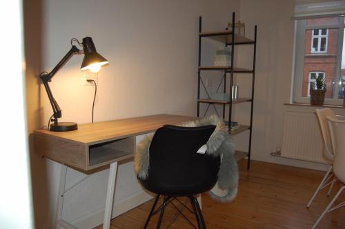 a desk with a black chair and a lamp at Lejlighed i Centrum in Fredericia