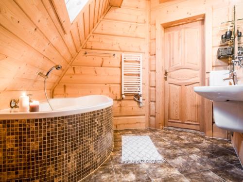 a wooden bathroom with a tub and a sink at TatryTop Panorama Lux Spa in Kościelisko