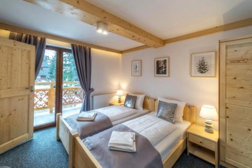 a bedroom with two beds and a large window at Villa Kaplowa Chata & SPA in Zakopane