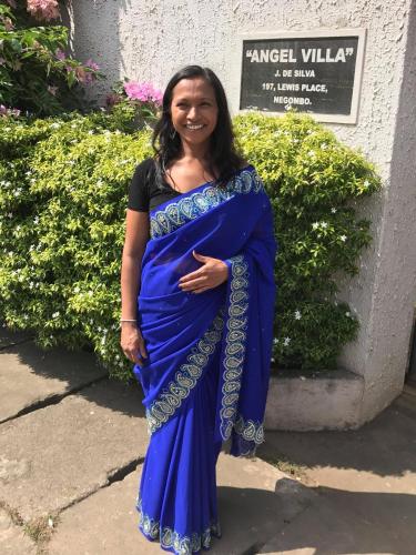 a woman in a blue dress standing in front of a sign at Angel villa in Negombo